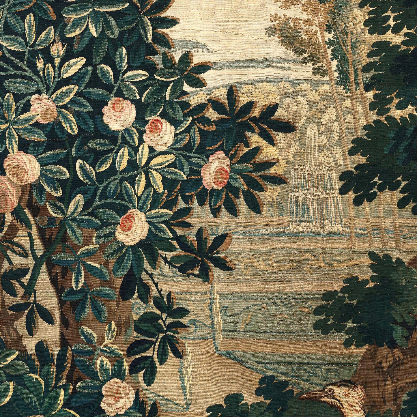 Pink rose bush in the foreground with a tiered stone fountain in the formal garden behind — design detail from the 18th-century French verdure chateau garden.
