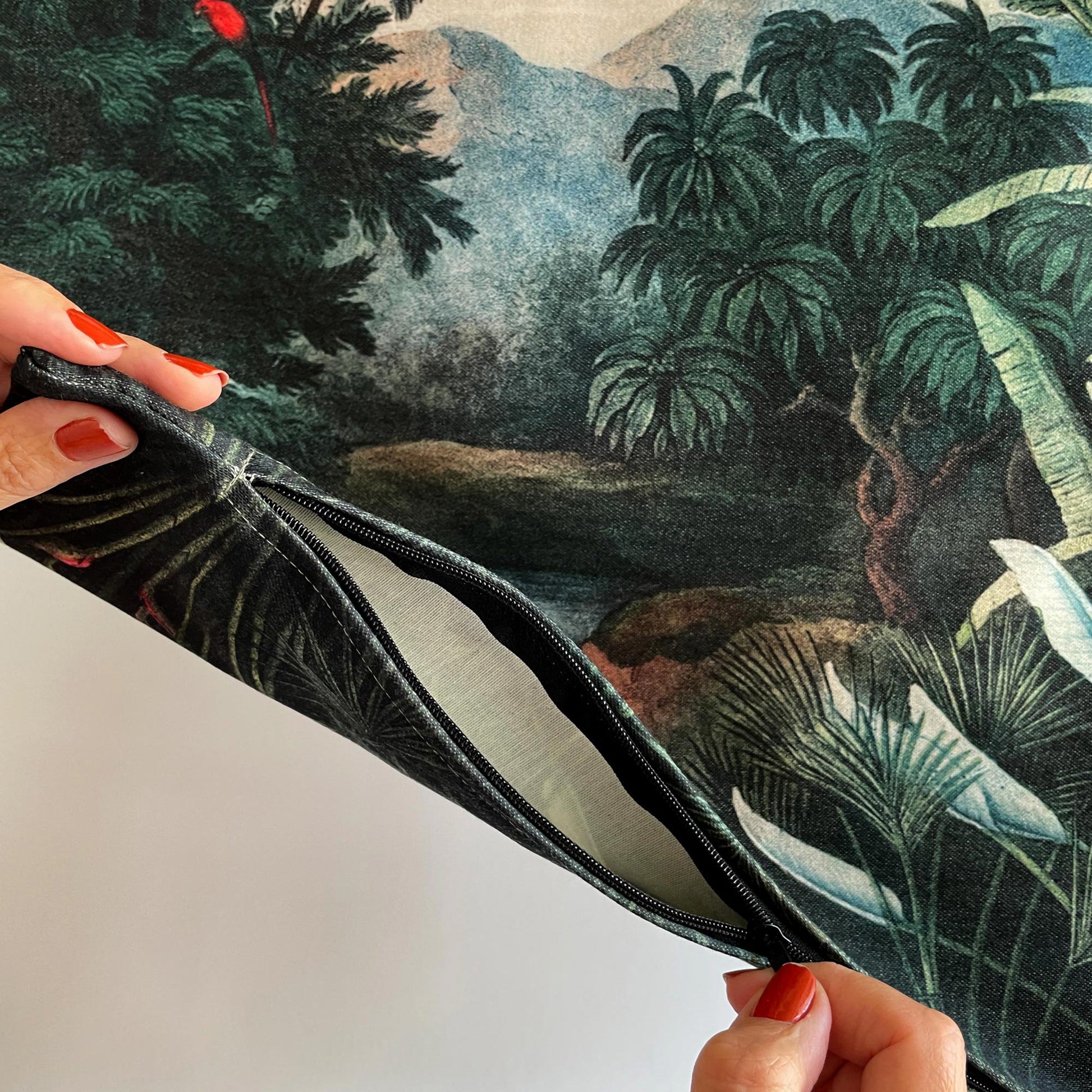 Hands unzipping the vintage tropical jungle pillow cover, showing the printed fabric and concealed closure.