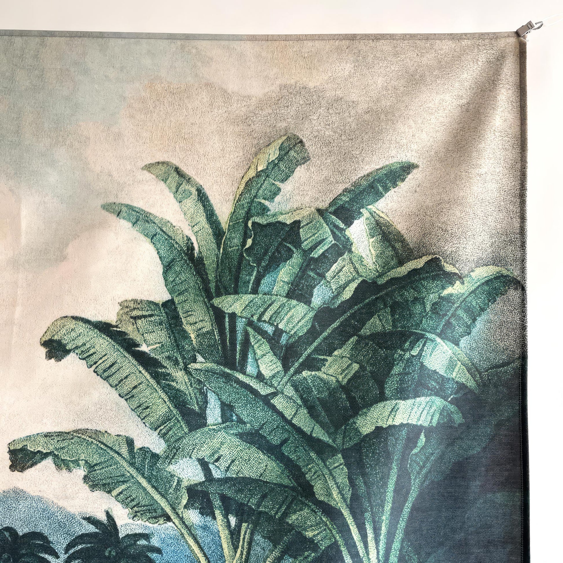 Detail of the top right corner of the tropical landscape hanging tapestry, revealing the high-quality print of large banana leaves and the fabric texture.