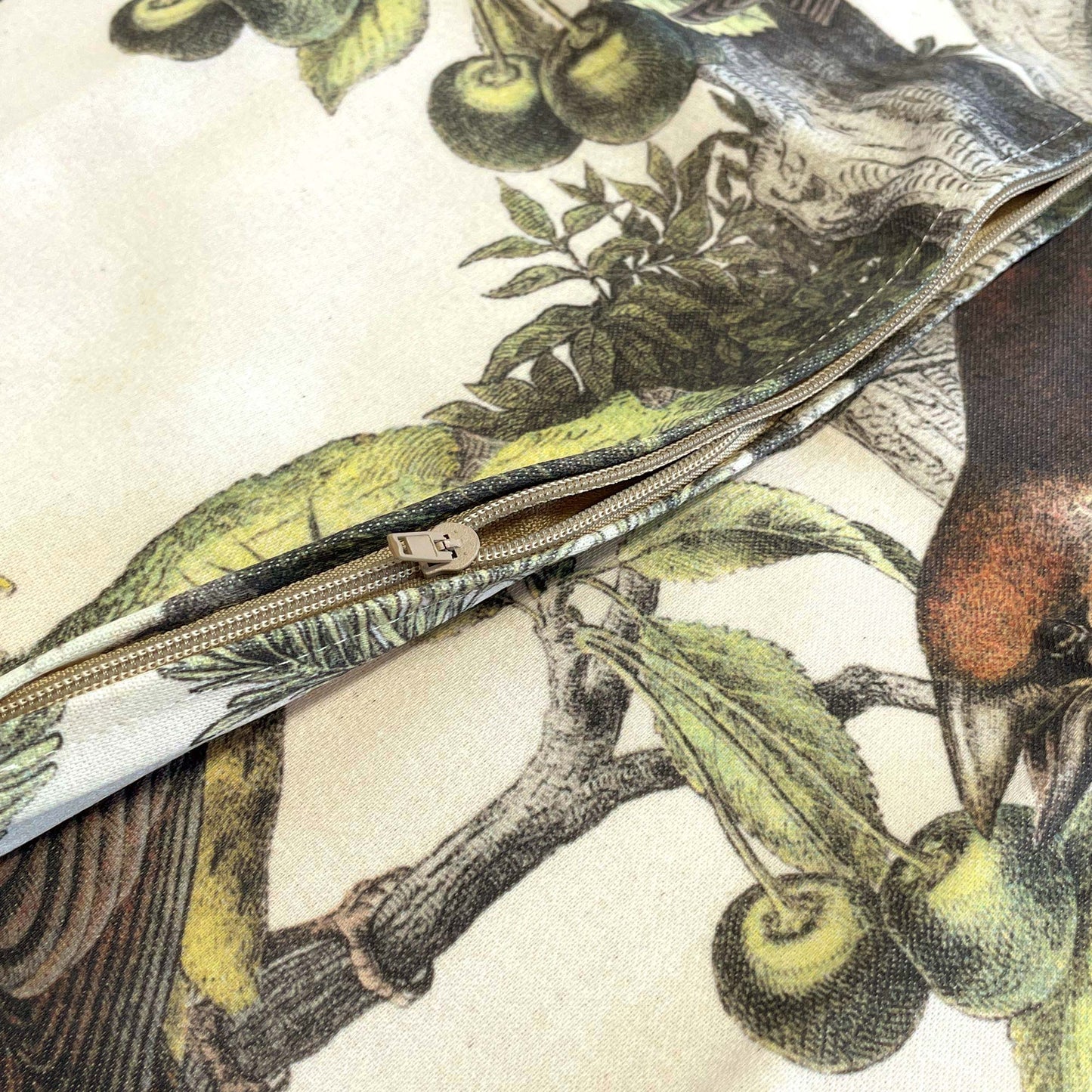 Close-up of the hidden zipper on the vintage finches cushion cover showing a printed bird eating cherries.