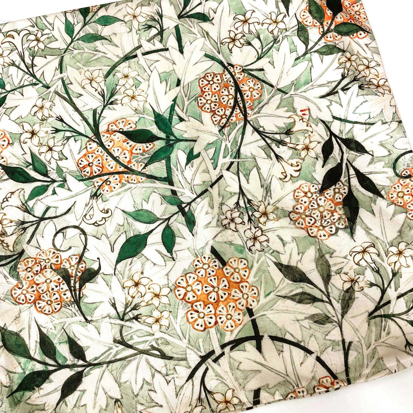 Flat lay of the William Morris Jasmine throw pillow cover showing the full interlacing green and peach floral repeat.