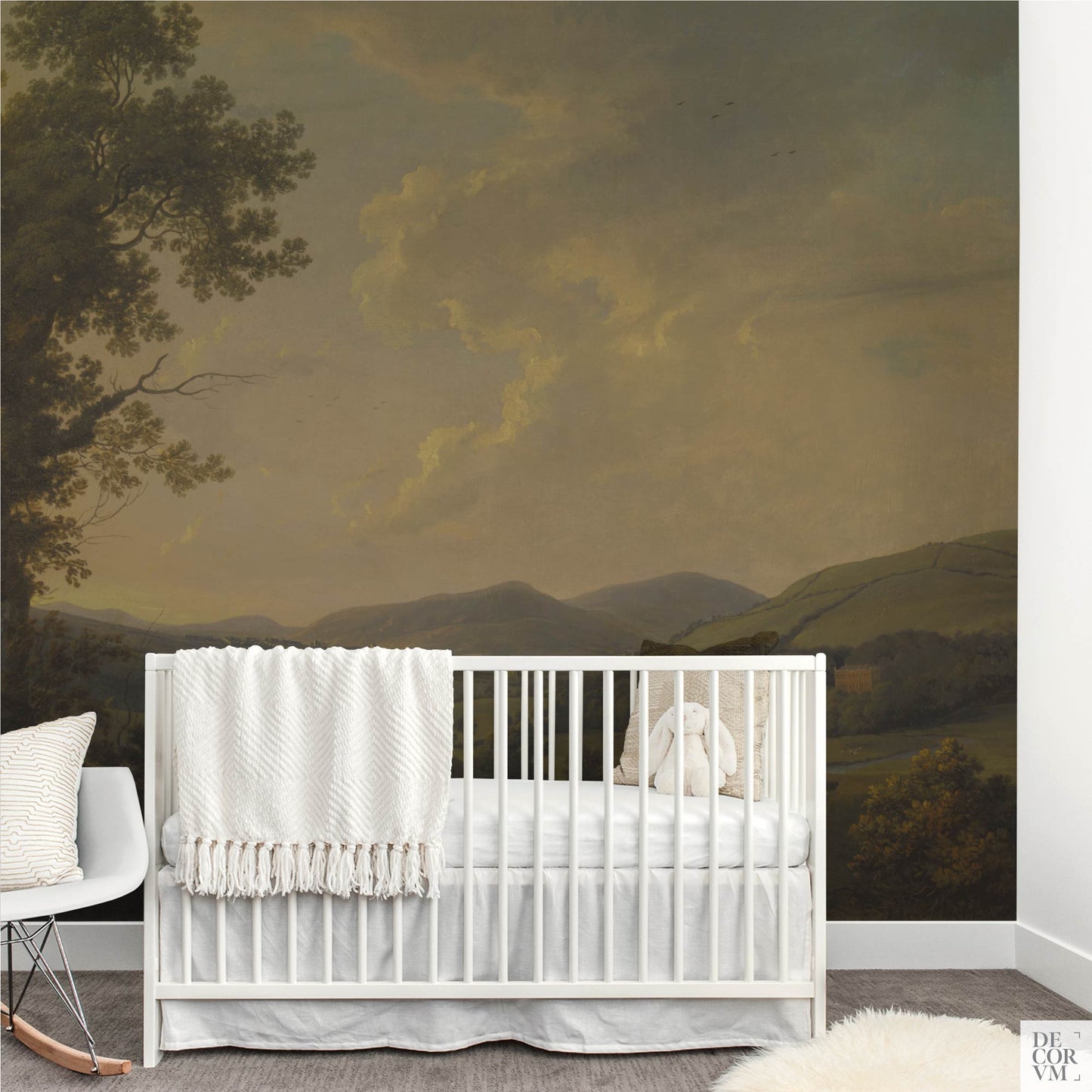 Gender-neutral nursery featuring a vintage English pastoral landscape wallpaper mural behind a white crib, creating a peaceful, nature-inspired scene for a baby room.