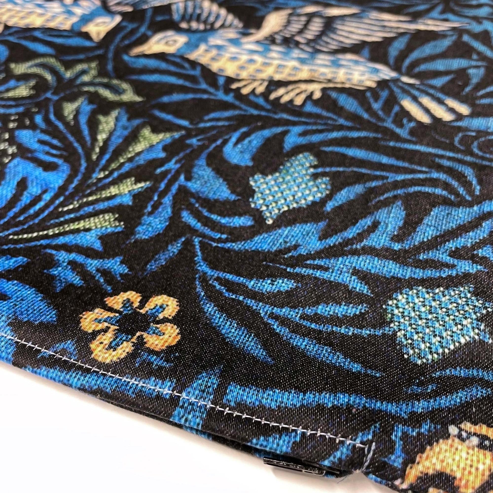 Bottom stitched corner of the William Morris Birds pillow cover showing the cotton-polyester weave and floral background.