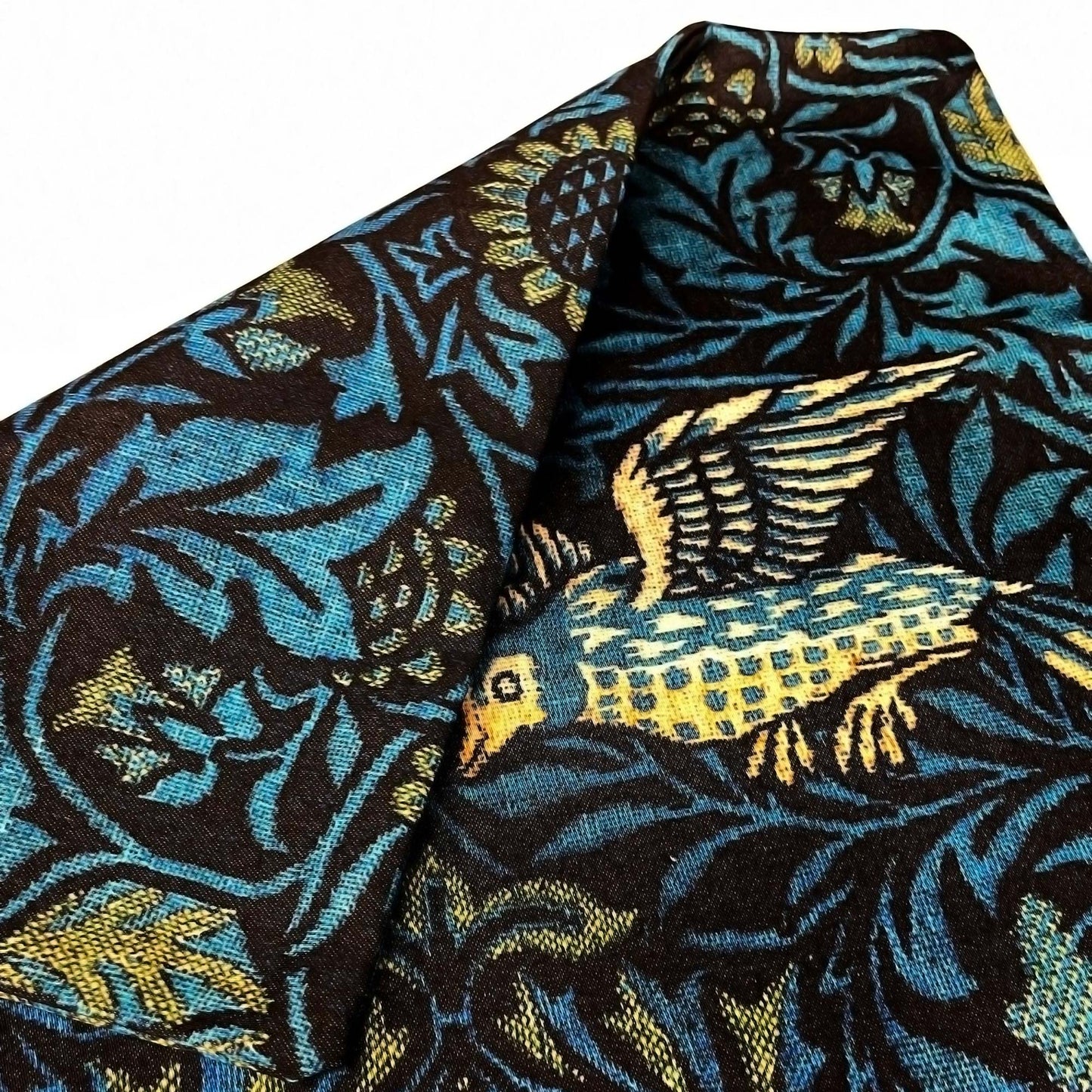 Folded William Morris Birds pillow cover showing the teal and navy fabric drape.