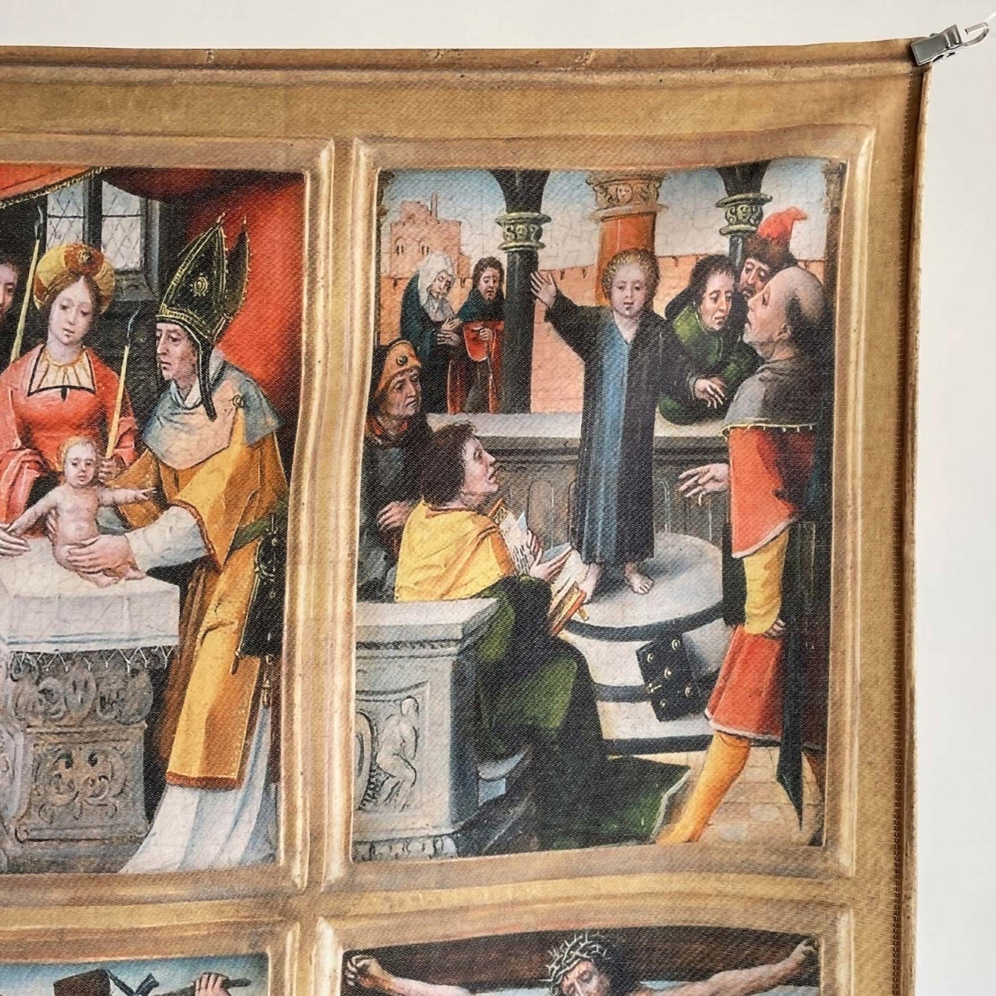 Detail of the religious tapestry showing biblical scenes including Jesus among the Doctors, with the top hem and hanging clip visible.