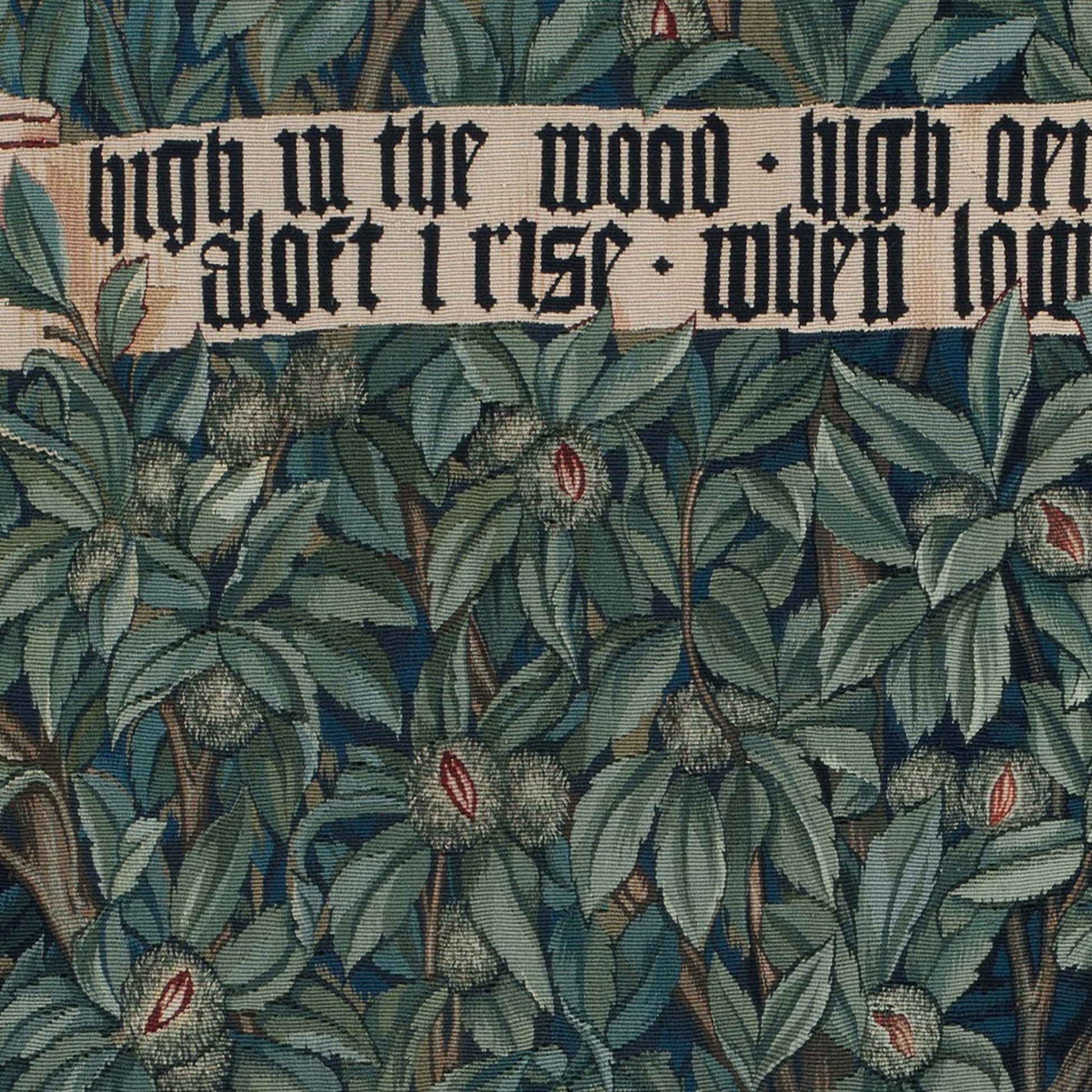 Detail of medieval gothic script reading 'High in the wood' surrounded by stylized green foliage and chestnut leaves — Greenery tapestry detail.