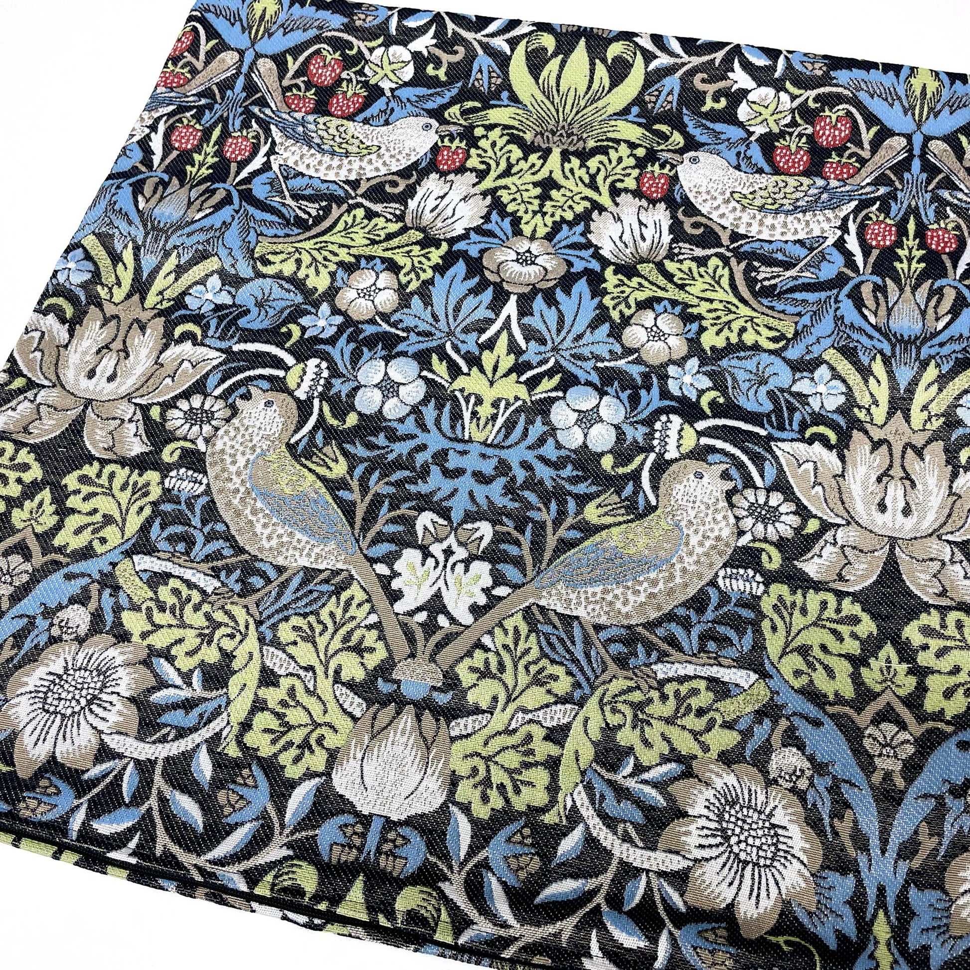 Angled flat lay of the William Morris Strawberry Thief jacquard pillow showing the woven pattern repeat.