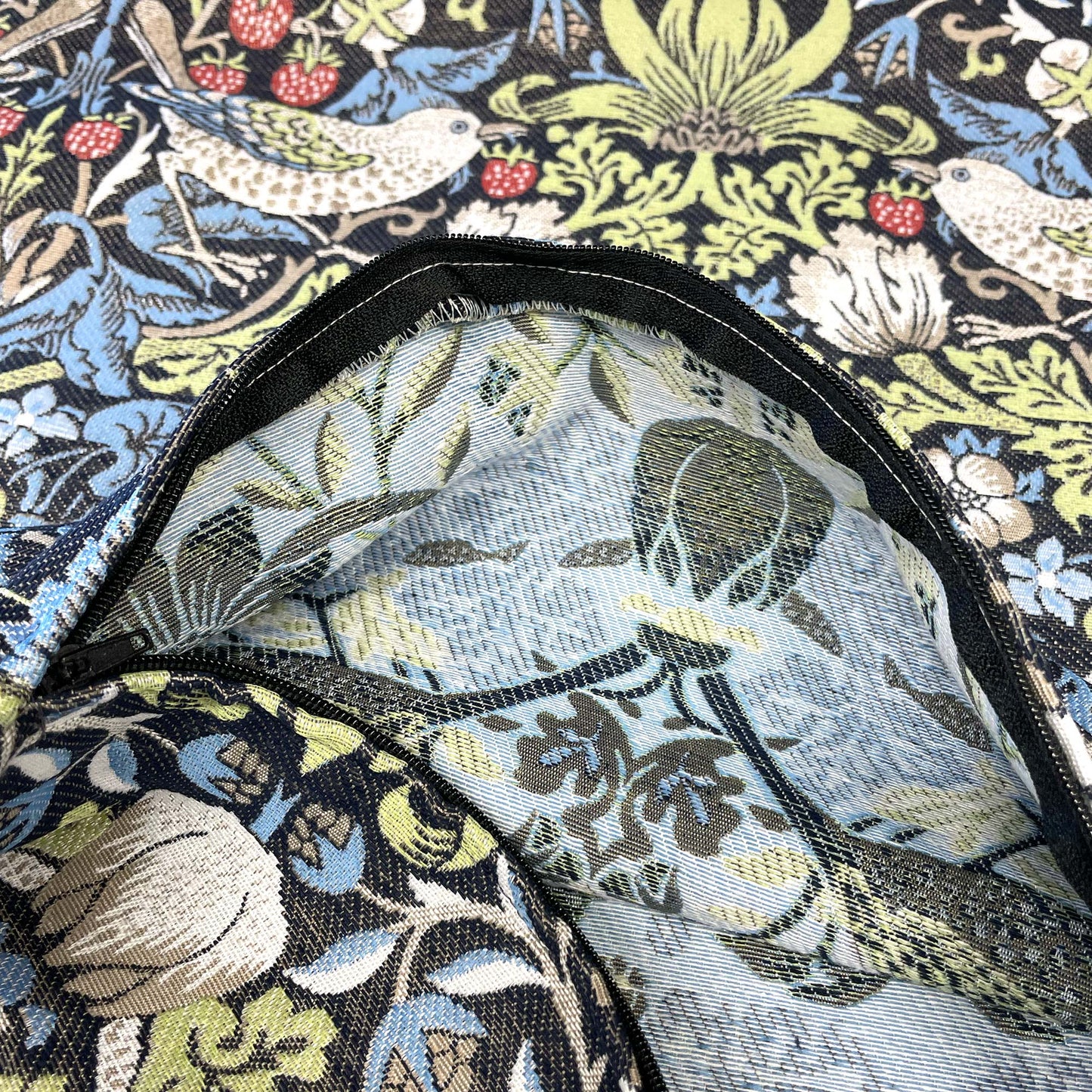 Reverse side of the William Morris Strawberry Thief jacquard pillow visible through the open zipper.